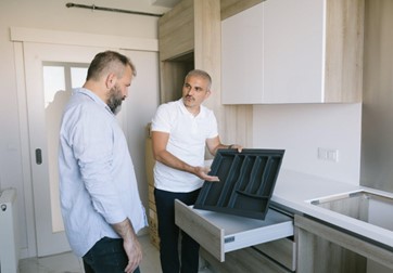 A landlord showing kitchen items to a tenant.