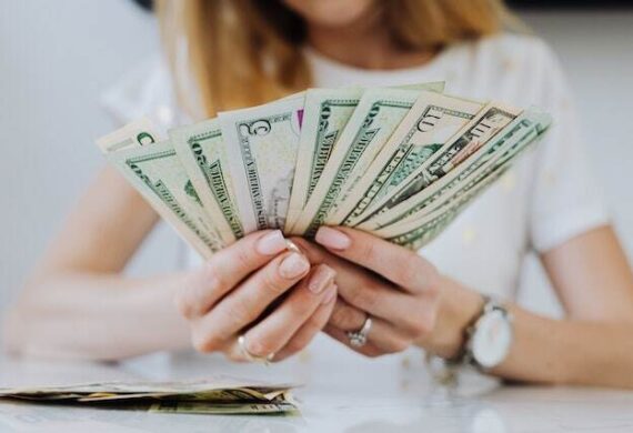 person-holding-rent-dollar-bills-splayed-out-in-their-hands